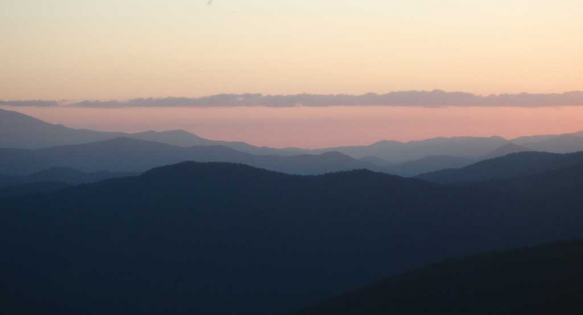 From a high elevation, the Blue Ridge mountains stretch for miles under the gentle colors of the sky.