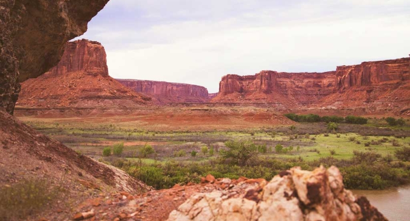 A desert landscape marked by tall red rock formations rests under gray skies 